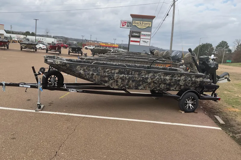 Slide: The Image of 2026 Excel 1751 Shallow Water F4 boat with camouflage design on trailer in parking lot. - 26
