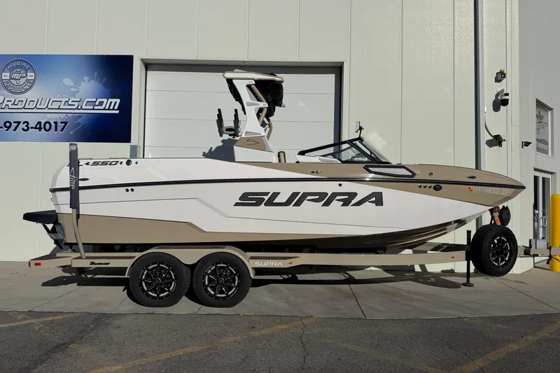 The Image of 2023 Supra SL 575 boat on trailer, parked outside a building. - 0
