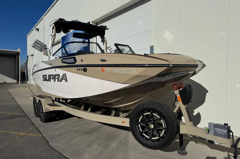 Slide: The Image of 2023 Supra SL 575 boat on trailer, parked outside a building. - 3