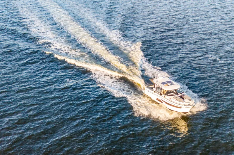 Slide: The Image of 2021 Jeanneau NC 1095 cruising on open water, leaving a wake behind. - 12