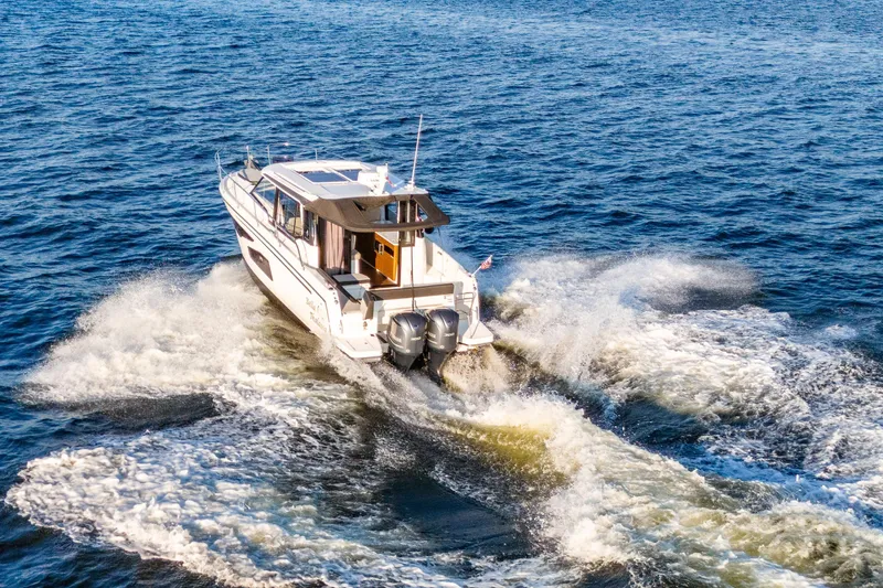 Slide: The Image of 2021 Jeanneau NC 1095 cruising on open water, creating a dynamic wake. - 19