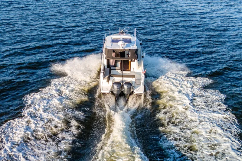 Slide: The Image of 2021 Jeanneau NC 1095 motorboat cruising on open water, rear view. - 21