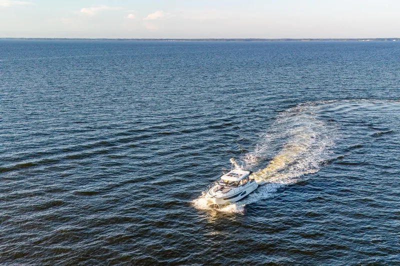 Slide: The Image of 2021 Jeanneau NC 1095 cruising on open water, leaving a wake behind. - 27