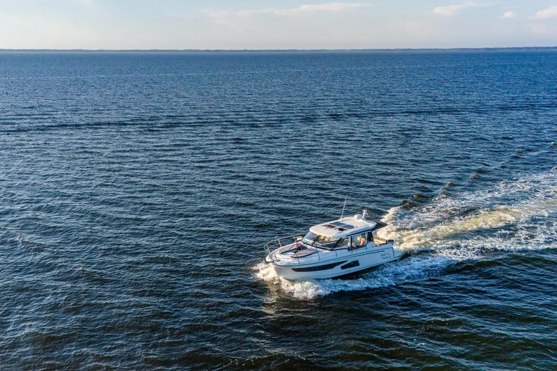 Slide: The Image of 2021 Jeanneau NC 1095 cruising on open water under a clear sky. - 6