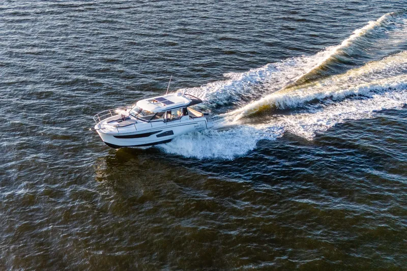 Slide: The Image of 2021 Jeanneau NC 1095 cruising on open water, creating a dynamic wake. - 9