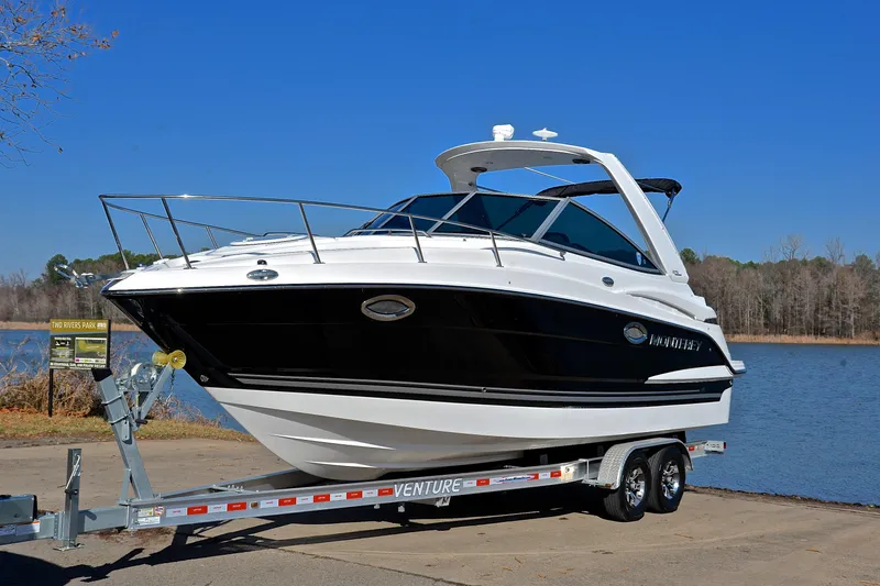 Slide: The Image of 2018 Monterey 275 Sport Yacht on trailer by a lake under clear blue sky. - 13
