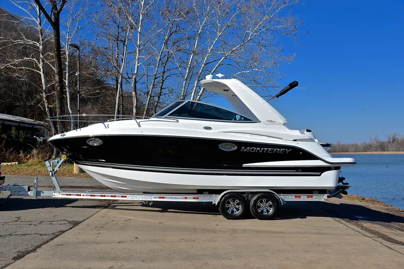 Slide: The Image of 2018 Monterey 275 Sport Yacht on trailer by a lake, clear blue sky. - 14
