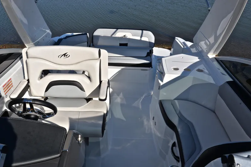 Slide: The Image of 2018 Monterey 275 Sport Yacht interior with white seating and steering wheel, docked by water. - 26