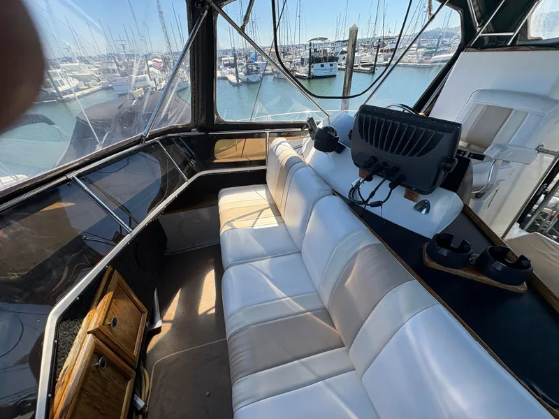 Slide: The Image of 1988 Carver 36 Aft Cabin interior with white seating and marina view. - 17