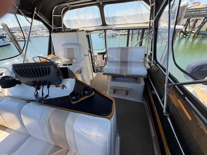 Slide: The Image of 1988 Carver 36 Aft Cabin interior with helm, seating, and marina view. - 18