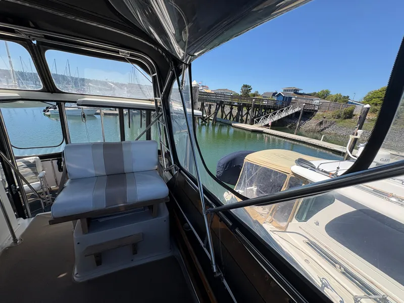 Slide: The Image of 1988 Carver 36 Aft Cabin interior view at marina, featuring seating and dockside scenery. - 19