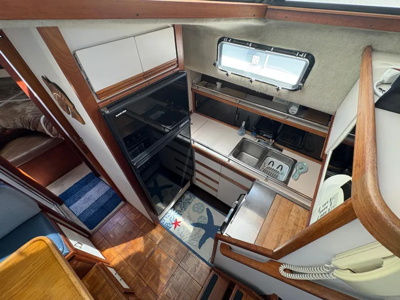 Slide: The Image of 1988 Carver 36 Aft Cabin kitchen with wood accents, sink, and appliances. - 26
