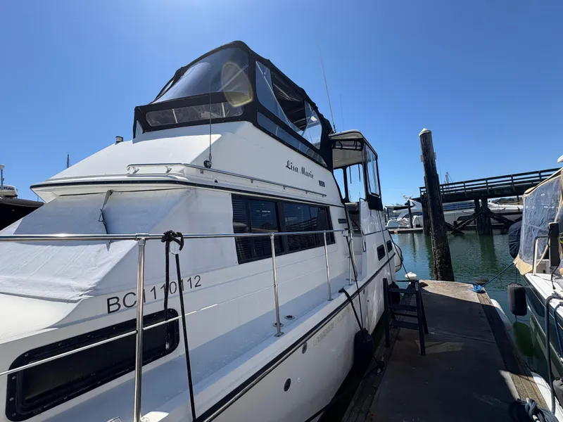 Slide: The Image of 1988 Carver 36 Aft Cabin yacht docked at marina under clear blue sky. - 3