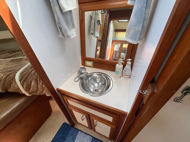 Slide: The Image of 1988 Carver 36 Aft Cabin bathroom with sink, mirror, and wooden cabinetry. - 35
