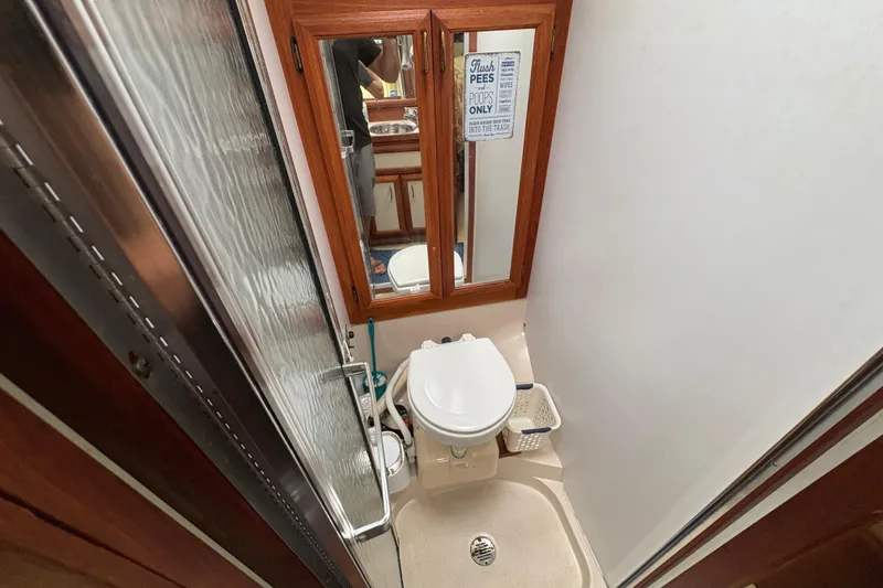 Slide: The Image of 1988 Carver 36 Aft Cabin bathroom with toilet, mirror, and shower area. - 36