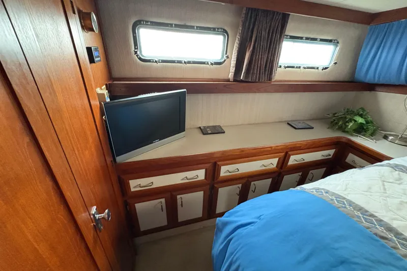 Slide: The Image of 1988 Carver 36 Aft Cabin interior with wood cabinetry, TV, and porthole windows. - 48