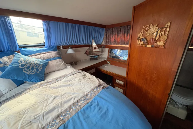 Slide: The Image of 1988 Carver 36 Aft Cabin bedroom with blue decor and wooden accents. - 49
