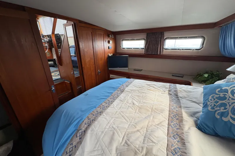 Slide: The Image of 1988 Carver 36 Aft Cabin interior with cozy bed, wooden cabinets, and small windows. - 52