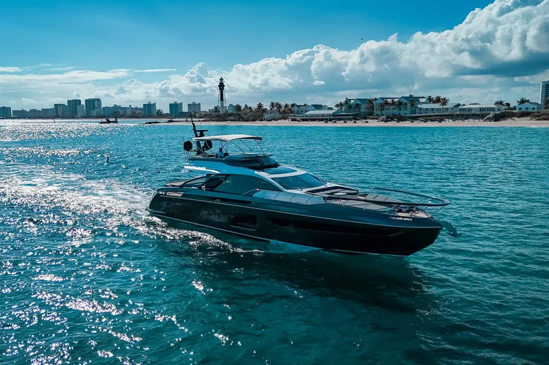 Slide: The Image of 2023 Azimut S8 yacht cruising on clear blue waters near a coastal cityscape. - 2