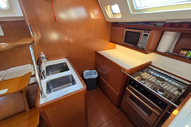 Slide: The Image of 2008 Beneteau Oceanis 49 yacht kitchen with dual sinks, stove, and microwave. - 26