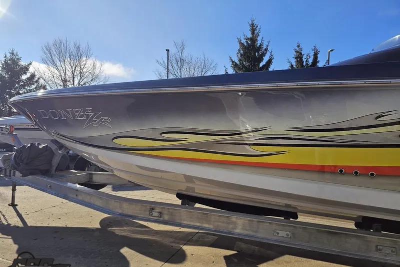 Slide: The Image of 2007 Donzi 38 ZR speedboat with vibrant graphics on a trailer under clear skies. - 23