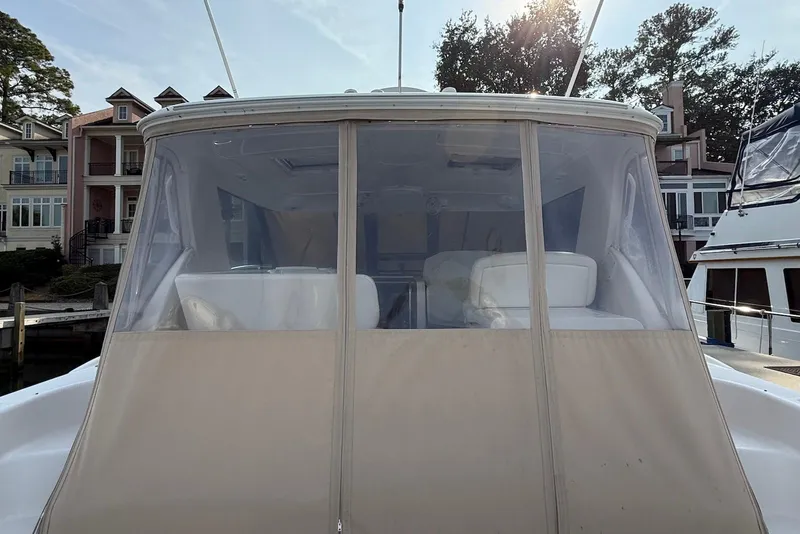 Slide: The Image of 2004 Tiara Yachts 3600 Sovran docked, featuring enclosed cockpit and waterfront homes in background. - 19