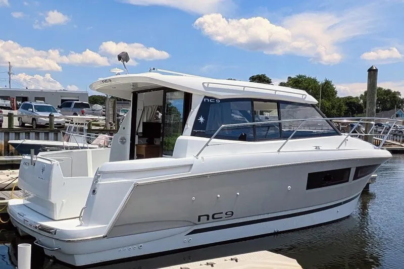 The Image of 2019 Jeanneau NC 9 boat docked at marina under blue sky. - 0