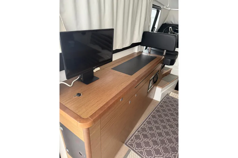 Slide: The Image of Interior of 2019 Jeanneau NC 9 boat with wooden cabinetry and a mounted monitor. - 10