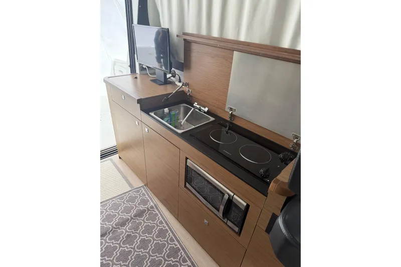 Slide: The Image of Compact kitchen in 2019 Jeanneau NC 9 boat with stove, sink, and microwave. - 11