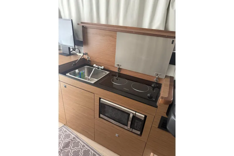 Slide: The Image of 2019 Jeanneau NC 9 boat kitchen with stove, sink, and microwave. - 12