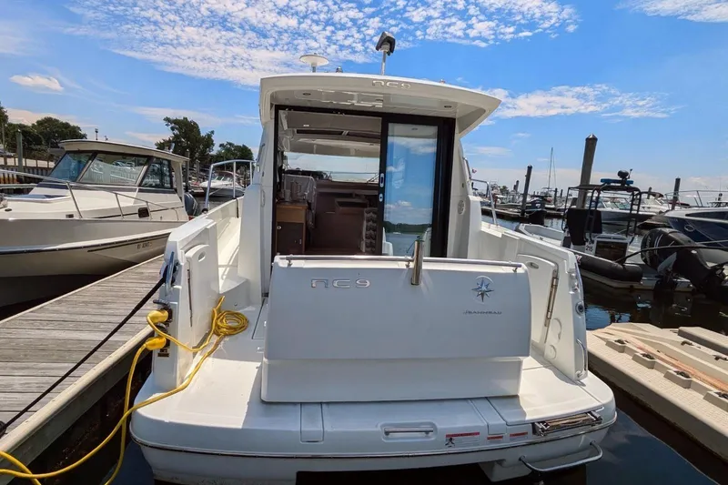 Slide: The Image of 2019 Jeanneau NC 9 docked at marina under blue sky. - 2