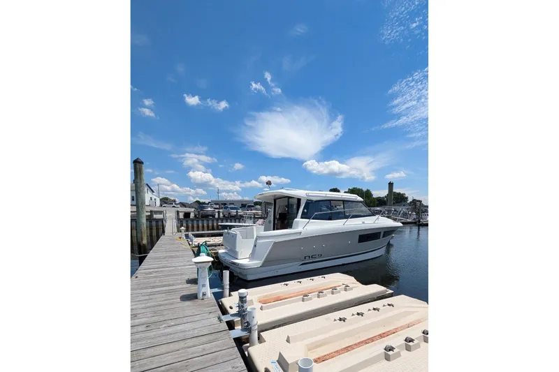 Slide: The Image of 2019 Jeanneau NC 9 docked at marina under clear blue sky. - 3