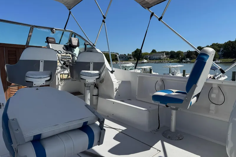 Slide: The Image of 1988 Chris-Craft 215 Sea Hawk boat interior with blue and white seating, docked by a marina. - 19