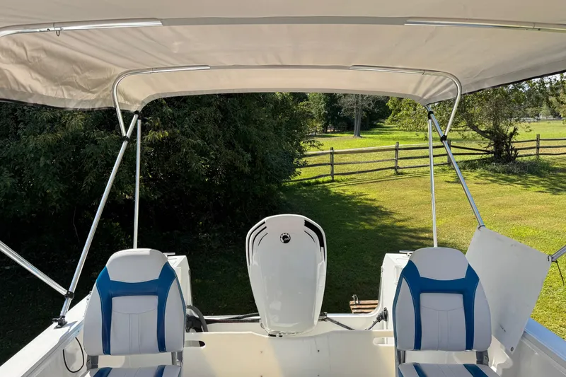 Slide: The Image of 1988 Chris-Craft 215 Sea Hawk boat interior with canopy and seating, set in a grassy area. - 33