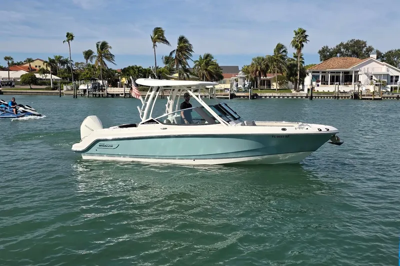 The Image of 2021 Boston Whaler 240 Vantage boat cruising on a sunny day near waterfront homes. - 1
