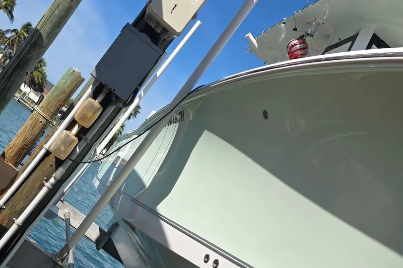 Slide: The Image of 2021 Boston Whaler 240 Vantage boat docked near wooden posts on a sunny day. - 13