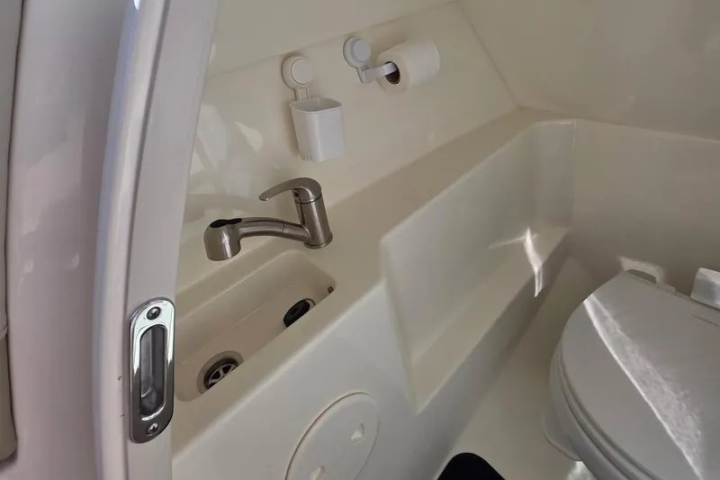 Slide: The Image of Interior of 2021 Boston Whaler 240 Vantage boat, featuring a compact bathroom with sink and toilet. - 26