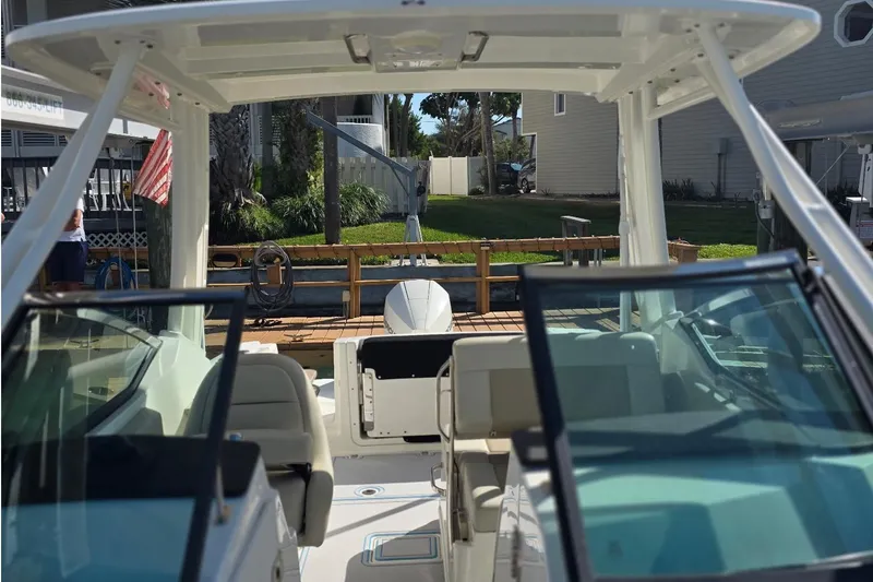 Slide: The Image of 2021 Boston Whaler 240 Vantage boat interior with seating and windshield, docked near a house. - 43