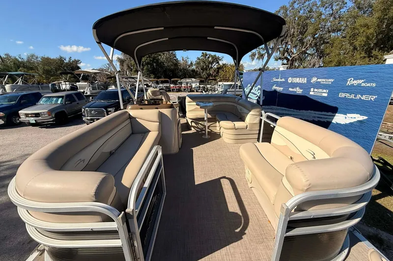 Slide: The Image of 2015 Bennington 20 SF pontoon boat with beige seating and canopy, displayed outdoors. - 2