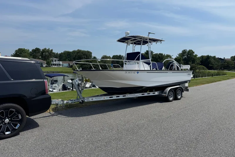 The Image of 2013 Boston Whaler 210 Montauk boat on trailer, parked near waterfront homes. - 1