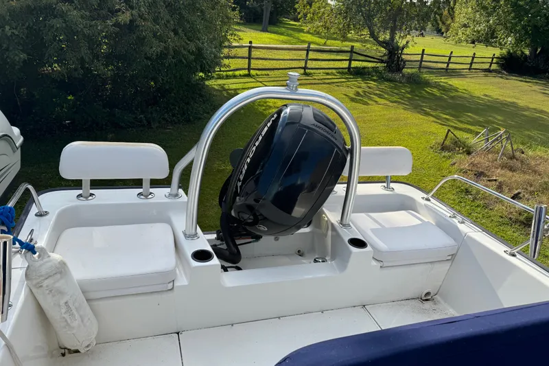 Slide: The Image of 2013 Boston Whaler 210 Montauk boat with Mercury engine, parked on grassy area. - 12