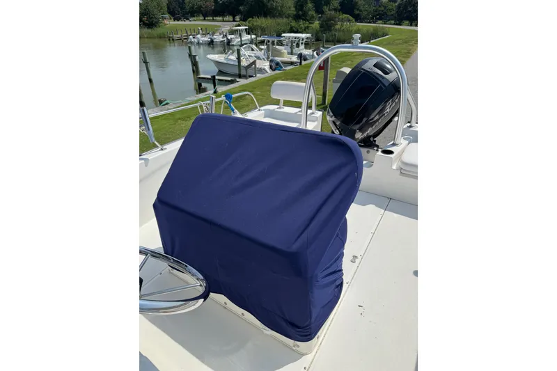 Slide: The Image of 2013 Boston Whaler 210 Montauk boat with covered console, docked near a scenic waterfront. - 13