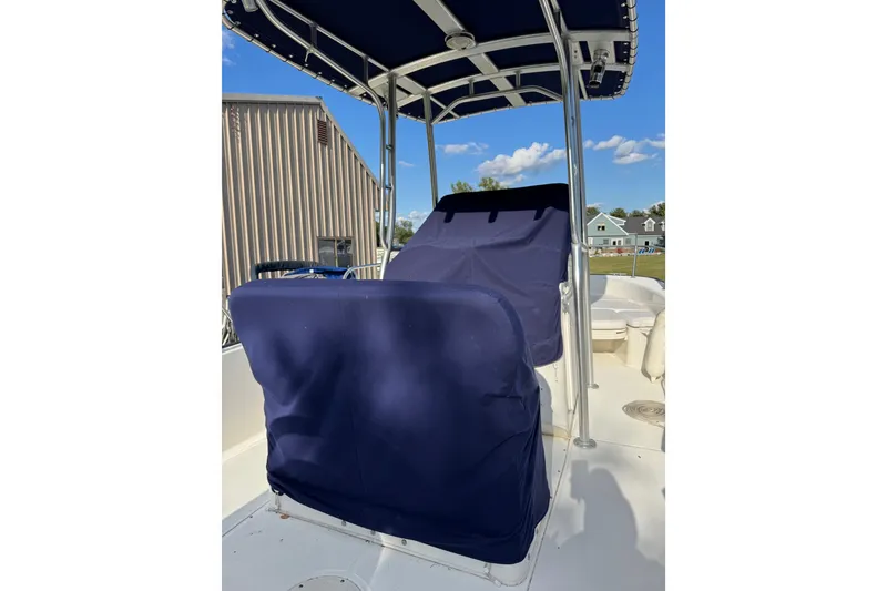 Slide: The Image of 2013 Boston Whaler 210 Montauk boat with blue seat covers and canopy, docked outdoors. - 25