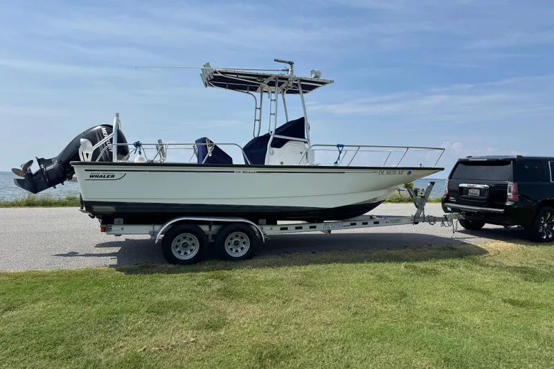 Slide: The Image of 2013 Boston Whaler 210 Montauk boat on trailer, parked near a black SUV. - 6