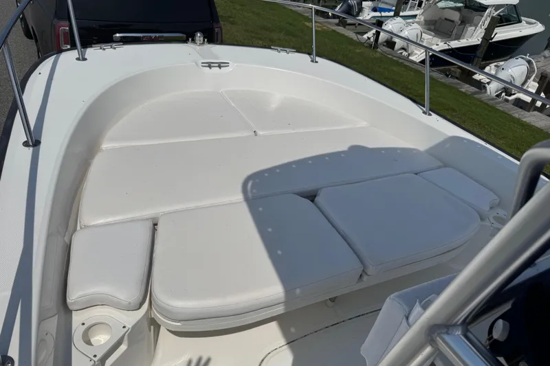 Slide: The Image of 2013 Boston Whaler 210 Montauk boat with cushioned seating area, docked near other boats. - 8