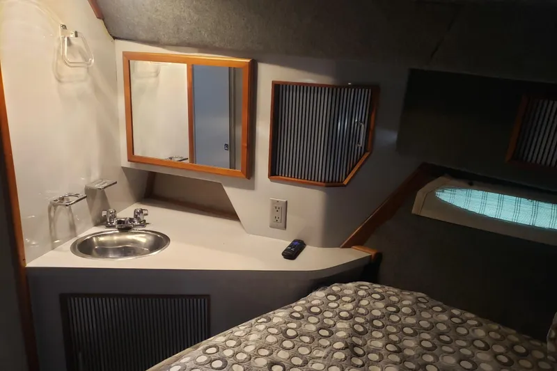 Slide: The Image of 1988 Sea Ray 390 Express Cruiser cabin interior with sink, mirror, and bed. - 11