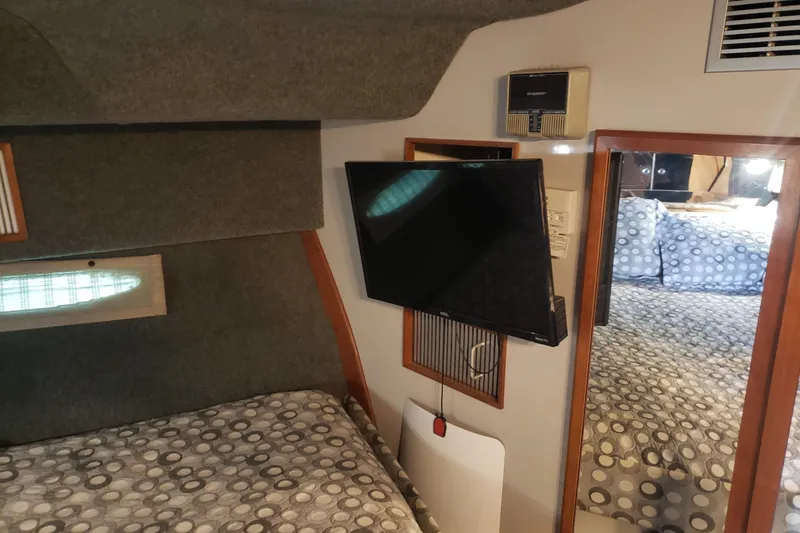 Slide: The Image of Interior of 1988 Sea Ray 390 Express Cruiser with TV, bed, and patterned bedding. - 12