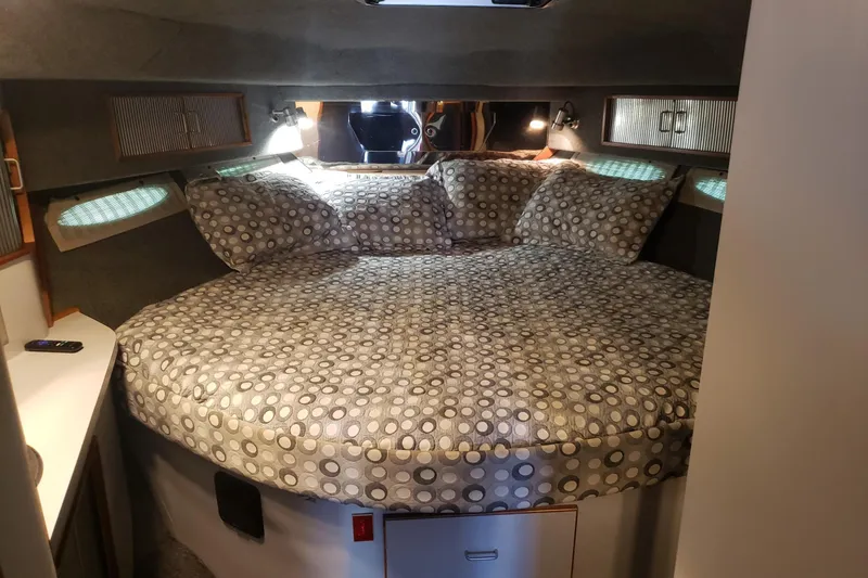 Slide: The Image of 1988 Sea Ray 390 Express Cruiser cabin with cozy bed and patterned bedding. - 13