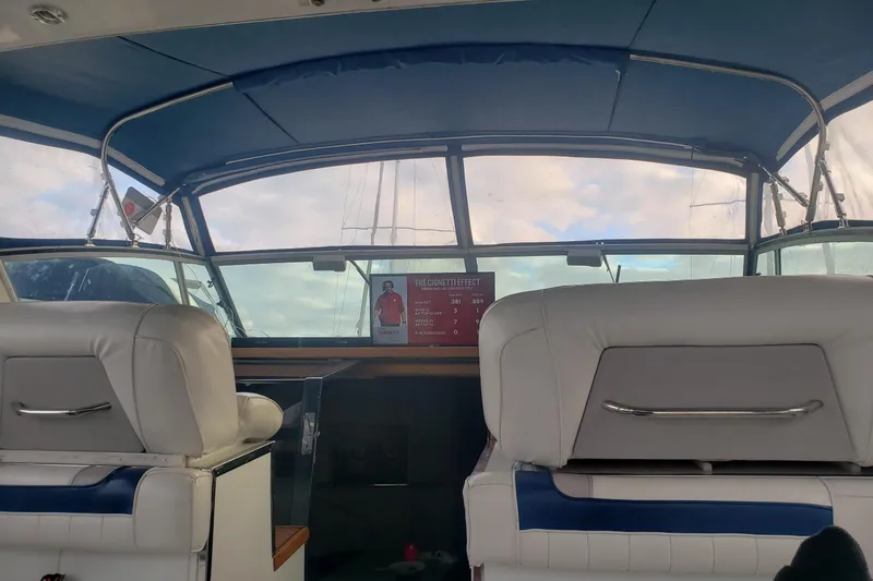Slide: The Image of 1988 Sea Ray 390 Express Cruiser interior with white seating and blue canopy. - 25