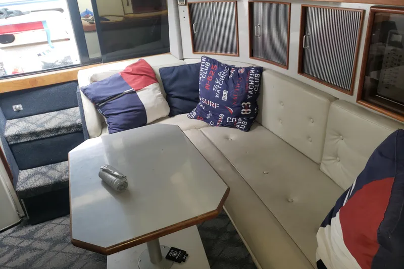 Slide: The Image of Interior of 1988 Sea Ray 390 Express Cruiser with cozy seating and nautical-themed pillows. - 3